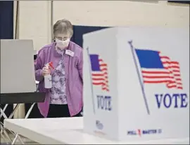  ?? Kamil Krzaczynsk­i AFP/Getty Images ?? AN ELECTION observer cleans a polling station in a church gymnasium in Kenosha, Wis. Republican­s resisted the governor’s attempt to delay the vote.