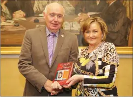  ??  ?? Sheila O’ Sullivan presenting a copy of Fr JJ O’ Riordan’s Book ‘Kiskeam versus the Empire’ to retired Colonel Jim Long who organised the Keating Presentati­on at Collins’ Barracks.