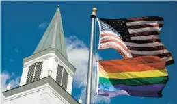  ?? CHARLIE RIEDEL/AP ?? A Pride flag flies along with the U.S. flag in front of the Asbury United Methodist Church in Prairie Village, Kansas.