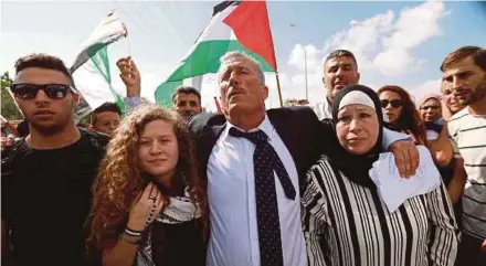  ?? REUTERS PIC ?? Ahed Tamimi (second from left) walking out after she was released from an Israeli prison at Nabi Saleh village in the occupied West Bank yesterday. With her are her parents, Bassem Tamimi and Nariman.