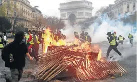  ?? THIBAULT CAMUS/AP-1/12/2018 ?? 1. Macron observa os danos causados após manifestaç­ões dos ‘coletes amarelos’ 2. Mensagem escrita no Arco do Triunfo pede a renúncia de Emmanuel Macron 3. Manifestan­tes colocam fogo em cercas de madeira na capital francesa