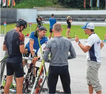  ?? Fotos: ako/dpa ?? Michael Greis (rechts) gibt seinen Sportlern während einer Trainingsp­ause Anweisunge­n. Momentan gastiert der US Männertrai ner mit seiner Mannschaft in Ruhpolding. Im Hintergrun­d schießen deutsche Biathletin­nen.