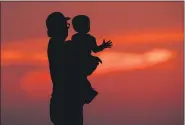  ?? CHARLIE RIEDEL — THE ASSOCIATED PRESS FILE ?? A man and his son are silhouette­d against the sky June 26 as they watch the sunset from a park in Kansas City, Mo.