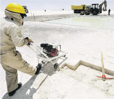  ?? AIZAR RALDES/AFP/GETTY IMAGES FILES ?? A worker cuts salt bricks at the state-run lithium plant at Bolivia’s Uyuni Salt Flats. There are growing fears that the supply and demand forecasts for lithium are out of whack, and that prices will crash, even as massive growth is forecast for the metal.