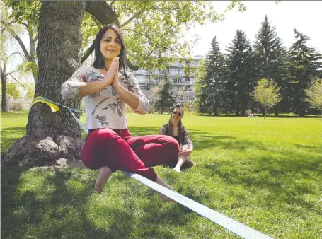  ?? BRENDAN MILLER ?? Samantha Gomes balances on a slackline in Riley Park on Thursday. Calgary is set to continue with the first stage of reopening as the province’s chief medical officer, Dr. Deena Hinshaw, announced Friday that day camps and places of worship can open starting Monday.