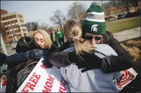  ?? JAKE MAY / THE FLINT JOURNAL VIA AP ?? Sue Dodde, a mother from Conklin, Mich., at right, embraces a student with a “free hug from a mom” as campus reopens for classes Monday at Michigan State University in East Lansing, Mich. A week ago, three students were killed and five others injured during a mass shooting at the university.