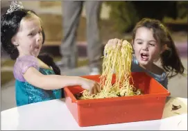  ?? Dan Watson/The Signal ?? Cora Bond, left, and Avery Pomeroy react as they put their hands into a “tray of worms” at the third annual Trunk-or-Treat event held at NorthPark Community Church in Valencia on Friday.