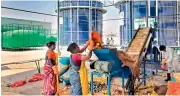  ?? — DC ?? A woman dumps vegetable waste on a conveyor belt that takes them to a biogas plant and a power plant at the Bowenpally vegetable market in Hyderabad.