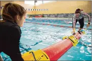  ??  ?? Wright-Patterson Air Force Base Life Guard Shelbi Bauer holds a synthetic log in place while Kaley Bartosik, WPAFB Outdoor Recreation director, climbs atop to demonstrat­e how to log roll. Outdoor Recreation offers two classes a month.