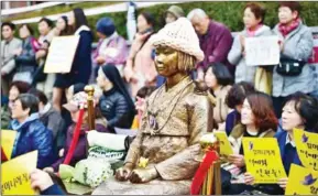  ?? JUNG YEON-JE /AFP ?? Protesters sit next to a statue of a South Korean girl in memory of ‘comfort women’ near the Japanese Embassy in Seoul on November 11, 2015.