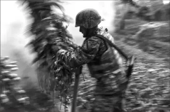  ?? Michael Robinson Chavez/The Washington Post ?? In this 2017 file photo, a soldier throws opium poppies onto a fire. In Mexico, nearly 70,000 acres of land are used to grow poppies to produce opium.