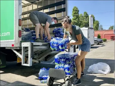  ?? GILLIAN FLACCUS — THE ASSOCIATED PRESS ?? Volunteers and Multnomah County employees unload cases of water to supply a 24-hour cooling center set up in Portland, Ore., Aug. 11, as a dangerous heat wave grips the Pacific Northwest.