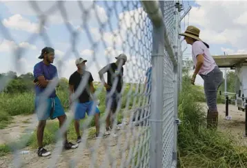  ?? ERIC GAY/AP ?? Magali Urbina, right, talks through her fence Aug. 26 to migrants crossing her pecan farm in Eagle Pass, Texas.