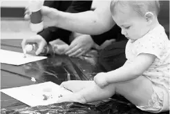  ?? JESSICA BAUDIN- GRIFFIN ?? Six-month-old baby Maryssa fingerpain­ts during an Intellidan­ce class for babies 0 to 12 months of age.