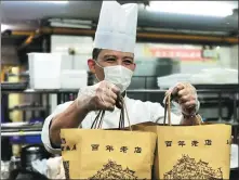  ?? PHOTOS PROVIDED TO CHINA DAILY ?? Left: A chef from Shanghai Classical Hotel’s restaurant presents takeaway lunch, a service the century-old restaurant has adopted for the first time to mitigate losses resulting from the ban on dine-in service during the COVID-19 outbreak. Right: Customers shop at Nanxiang Mantou, a restaurant famous for its steamed meat-stuffed buns, in Shanghai.