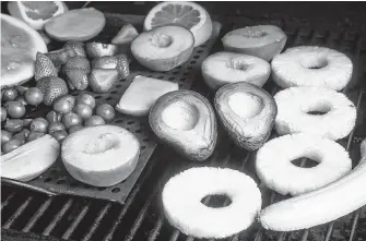  ?? Marvin Pfeiffer / San Antonio Express-News ?? The sliced avocados begin to take on a smoky appearance along with other fruits on the grill, but some fared better than others.