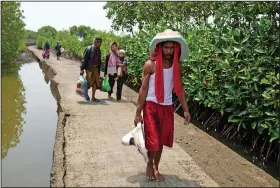  ?? ?? Aslori carries toilets he recovered from his and a relative’s house Sept. 5 as he and several neighbors return from visiting their old abandoned houses in Mondoliko, Indonesia.