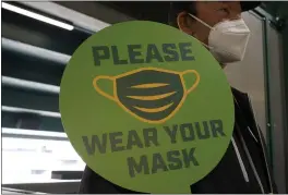  ?? JEFF CHIU — THE ASSOCIATED PRESS FILE ?? A stadium worker holds up a sign for people to wear face masks before a baseball game between the Oakland Athletics and the Houston Astros in Oakland As the world struggles to break the grip of COVID-19, psychologi­sts and misinforma­tion experts are studying why the pandemic spawned so many conspiracy theories, which have led people to eschew masks, social distancing and vaccines.