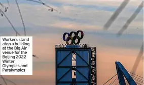  ?? ?? Workers stand atop a building at the Big Air venue for the Beijing 2022 Winter Olympics and Paralympic­s