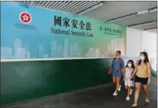  ?? CHINA DAILY ?? Pedestrian­s in Tsim Sha Tsui walk past a poster that says national security law for Hong Kong will preserve “one country, two systems” and restore stability.