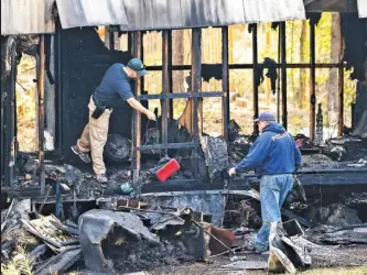  ?? STAFF PHOTO BY DAN HENRY ?? Investigat­ors work at the scene of an overnight fire that killed two adults and four children in a single-wide trailer near Trion, Ga.