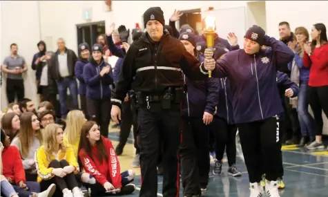  ?? DARREN MAKOWICHUK ?? Edmonton Police Const. Catlin Chiasson and student Ami Schaan, along with members from the Alberta Law Enforcemen­t Torch Run team, bring the Special Olympics torch to Bert Church High School in Airdrie, on Thursday.