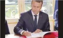  ?? — AFP ?? Macron signs documents in front of the media to promulgate a new labour bill in his office at the Elysee Palace in Paris, on Friday.