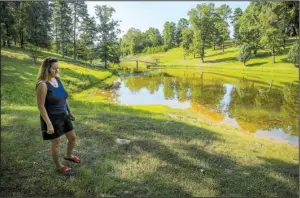  ?? Arkansas Democrat- Gazette/ STEPHEN B. THORNTON ?? Lisa Baxley walks past the pond on a 10- acre lot that she and her husband own in Saline County. She said sediment and debris runoff from a nearby residentia­l developmen­t has ruined the pond.