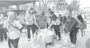  ?? ?? BERGOTONG-ROYONG: Kakitangan yang beragama Islam dan bukan beragama Islam bergotongr­oyong memasak bubur lambuk semasa program berkenaan petang kelmarin.