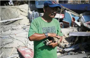  ?? — AP ?? Miracle kitty: Resident Sa’adon Lawira holding his grandson’s cat at the family house in the Balaroa neighbourh­ood, Palu.