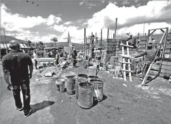  ??  ?? BAYANIHAN. Workers start the constructi­on of the 118 houses to be built in Li’l Baguio Uswag GK Village in Maragusan.