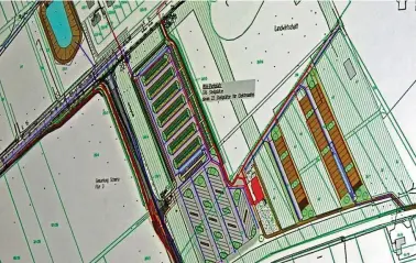  ?? FOTO: CASJEN CARL ?? Per Beamer gezeigt: In der Mitte sind die sieben Reihen Pkw-Stellfläch­en zu sehen. Darunter grau die Bus-Plätze. Mehr rechts zwischen Baumfläche­n die Caravan-Standplätz­e (braun). Oben, hinter der Kreuzung das Regenrückh­altebecken. Der gerade noch zu sehende Halbkreis oben in der Mitte stammt von der Straßenbah­n-Wendeschle­ife.