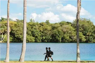  ?? ?? Fishermen walk next to the west lake at Snyder Park in Fort Lauderdale on Thursday. A pickleball complex with 42 courts is planned adjacent to the lake.