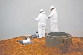  ?? STAFF PHOTO ?? Mark Greer, left, and Greg Schwartz take water samples in 2016 at the site where an overnight leak formed at the Kingston fossil plant’s Gypsum pond, leaking contaminat­ed water into the Clinch River in Harriman, Tenn.