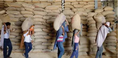  ?? Reuters ?? ↑
Workers carry sacks of wheat for sifting at a grain mill on the outskirts of Ahmedabad.