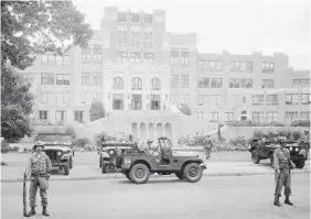  ?? AP FILE PHOTO ?? Members of the 101st Airborne Division take up positions in 1957 outside Central High School in Little Rock, Ark. The troops were on duty to enforce integratio­n at the school. On Monday, a teacher and two students from the school sued Arkansas over the state’s ban on critical race theory.