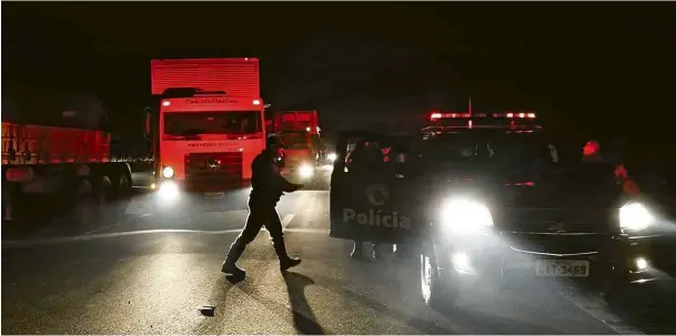  ?? Miguel Schincario­l/AFP ?? Policiais militares durante operação para liberar trecho do Rodoanel em São Bernardo do Campo (SP) na noite deste sábado (26)