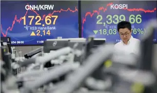  ?? — AP ?? A currency trader stands near screens showing the Korea Composite Stock Price Index and the foreign exchange rate at a foreign exchange dealing room in Seoul.