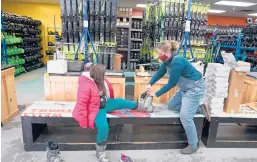  ?? CHARLESKRU­PA/AP ?? Meredith Hopkins helps fit ski boots onMakenna Houghton onDec. 16 at the ski shop at McIntyre Ski Area in Manchester, NewHampshi­re.