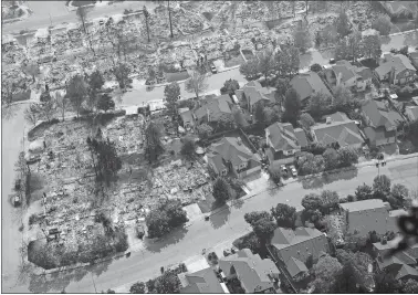  ?? RICH PEDRONCELL­I/AP PHOTO ?? Burned-out homes are seen Wednesday next to homes that survived the flames of a massive wildfire in the Coffey Park area of Santa Rosa, Calif.