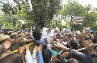  ?? Manish Swarup / Associated Press ?? Congress Party workers help their leader cross a police barricade during a protest accusing the government of using militarygr­ade spyware to monitor political opponents in New Delhi.