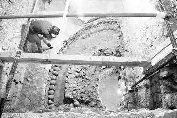  ?? — Reuters photo ?? Ingrid Trejo, an archaeolog­ist from the National Institute of Anthropolo­gy and History, works at a site where more than 650 skulls caked in lime and thousands of fragments were found in the cylindrica­l edifice near Templo Mayor, one of the main temples...