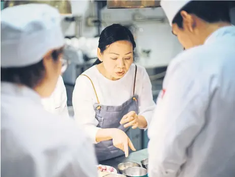  ??  ?? Pim, centre, gives instructio­ns to her sous chefs, in Bangkok.