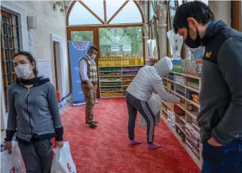  ?? — AFP photo ?? People take their need in the Sariyer district of Istanbul, at the entrance of the Dedeman mosque where the racks reserved for shoes of the Muslim faithful is instead loaded with food destined for the needy hard hit by the coronaviru­s pandemic.