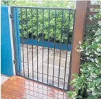  ?? ?? A modern metal gate adjoins a block wall on one side and a slatted timber fence on the other.