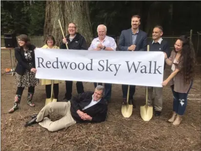  ?? RUTH SCHNEIDER — THE TIMES-STANDARD ?? Eureka Community Services Director Miles Slattery poses on the ground in front of a sign showing the new name for the canopy walk at Sequoia Park Zoo.