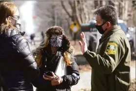  ?? H John Voorhees III / Hearst Connecticu­t Media file photo ?? Nancy Burton, center, with friend Tracey Hansen, left, talks with Officer Charles DellaRocco of the Connecticu­t Department of Agricultur­e as the department removed goats from her Redding property at 147 Cross Highway on March 10, 2021. The state has taken custody of more than 90 goats seized in an animal cruelty case and is offering them for adoption. Burton was later charged with 65 counts of cruelty to animals. She has pleaded not guilty.