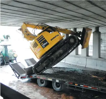  ?? PHOTO ANTOINE LACROIX ?? Une pelle mécanique transporté­e par un camion s’est encastrée dans un viaduc à Montréal, hier matin. Ce n’est qu’en fin de journée que les engins ont pu être sortis.