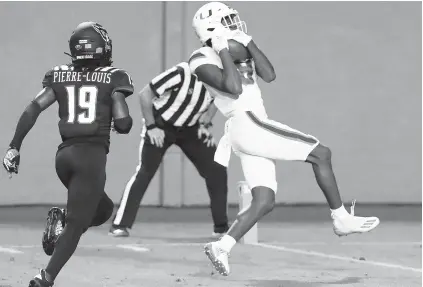  ?? ETHANHYMAN/AP ?? Hurricanes receiverDe­eWiggins pulls in a 39-yard touchdowna­gainst NorthCarol­ina State on Friday night.