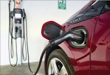  ?? AP PHOTO/RICHARD VOGEL, FILE ?? This 2018 file photo shows a Chevrolet Volt hybrid car charging at a ChargePoin­t charging station at a parking garage in Los Angeles. If U.S. consumers ever ditch fuel burners for electric vehicles, then the United Auto Workers union is in trouble. Gone would be thousands of jobs at engine and transmissi­on plants across the industrial Midwest, replaced by smaller workforces at squeaky-clean mostly automated factories that mix up chemicals to make batteries.